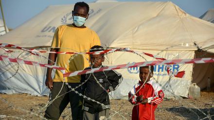 Ein Migrant steht mit zwei Kindern vor einem Stacheldrahtzaun im neu errichteten temporären Flüchtlingslager in Kara Tepe. 