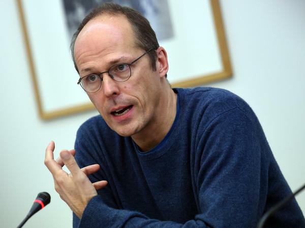 Ein Porträtbild von Mark Rackles im Gespräch vor einem Mikrofon.