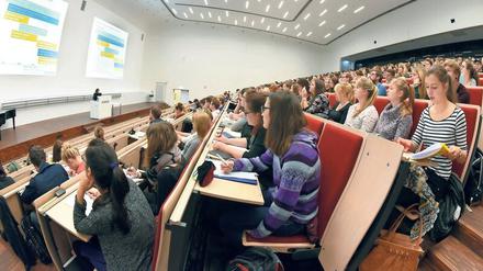 Studierende sitzen in einem gut gefüllten Hörsaal, über ihnen leuchtet eine Lichtdecke.