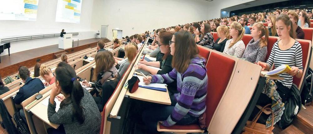 Studierende sitzen in einem gut gefüllten Hörsaal, über ihnen leuchtet eine Lichtdecke.
