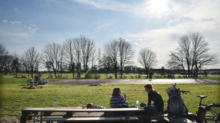 Zwei junge Frauen sitzen auf dem Tempelhofer Feld an einer Biertischgarnitur und picknicken.