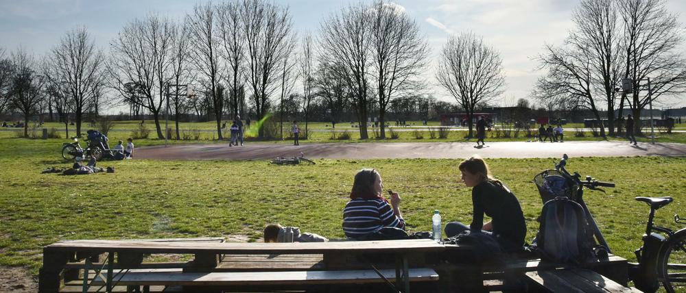 Zwei junge Frauen sitzen auf dem Tempelhofer Feld an einer Biertischgarnitur und picknicken.
