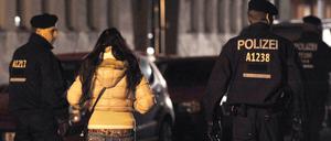 Polizisten begleiten bei einem Polizeieinsatz in Berlin eine Frau.