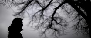 Depressive Frau vor einem Baum.
