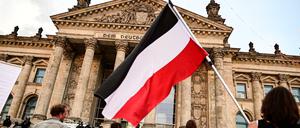 Ein Teilnehmer einer Kundgebung gegen die Corona-Maßnahmen schwenkt eine Reichsflagge vor dem Reichstagsgebäude.