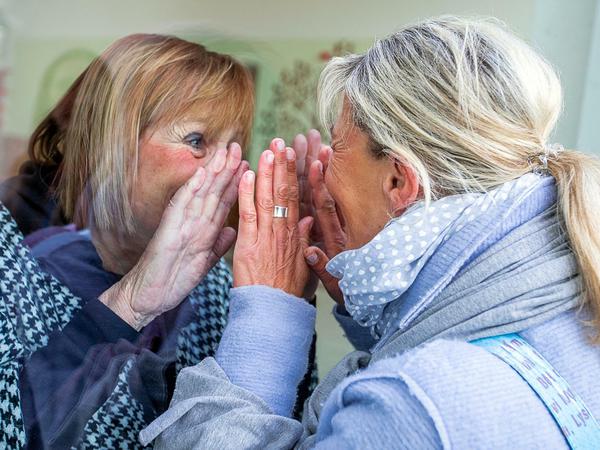So ist es ganz sicher: Eine Frau besucht ihre Mutter - aber sieht sie nur durch eine Scheibe.