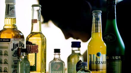Ein Jugendlicher sitzt hinter Flaschen mit Alkohol.