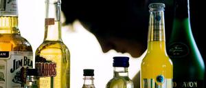 Ein Jugendlicher sitzt hinter Flaschen mit Alkohol.