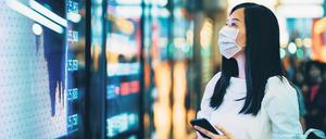 Besorgter Blick. Eine Businessfrau checkt in Hongkong die Aktienkurse auf einem Monitor.