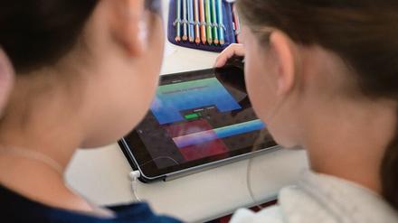 Zwei Schülerinnen arbeiten gemeinsam auf einem Tablet-Computer an einer Aufgabe.