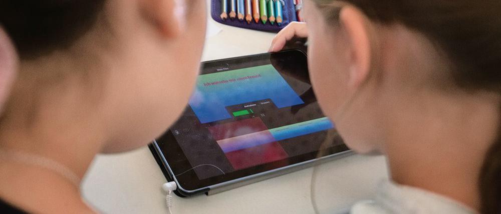 Zwei Schülerinnen arbeiten gemeinsam auf einem Tablet-Computer an einer Aufgabe.