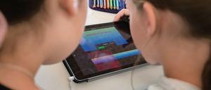 Zwei Schülerinnen arbeiten gemeinsam auf einem Tablet-Computer an einer Aufgabe.