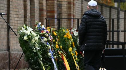 Ein Mitglied der jüdischen Gemeinde steht vor der Synagoge an Gedenkkränzen.