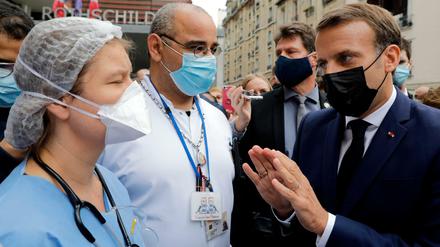 Frankreichs Präsident Emmanuel Macron (rechts) diskutiert in Paris mit Beschäftigten im Gesundheitssektor über deren Arbeitsbedingungen. 