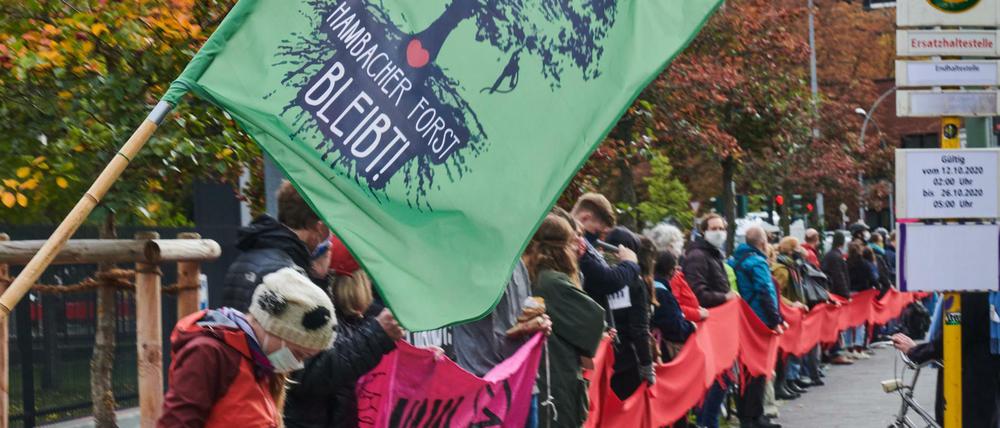 Mit rotem Band. "Hambacher Forst bleibt!" steht auf einer Fahne eine Menschenkette vor dem Verkehrsministerium.