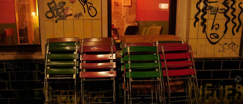 Kurz nach der Sperrstunde stehen zusammengeklappte Stühle vor einer Bar in Neukölln. 