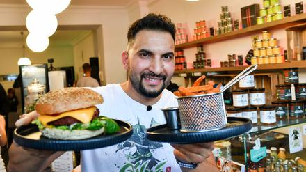 Früher fürs kochen berühmt, heute für rechtsradikale Thesen: Attila Hildmann steht bei einem Pressetermin in seinem veganen Imbiss und präsentiert einen veganen Burger. Jetzt wird gegen ihn protestiert.