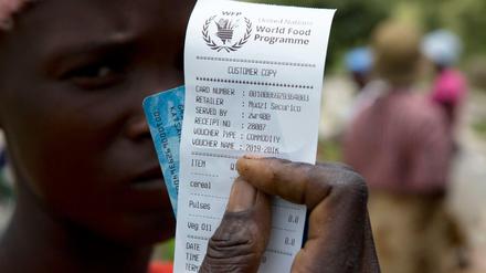 Eine Frau in Zimbabwe hält einen Gutschein für Nahrungsmittelhilfe in die Kamera. 