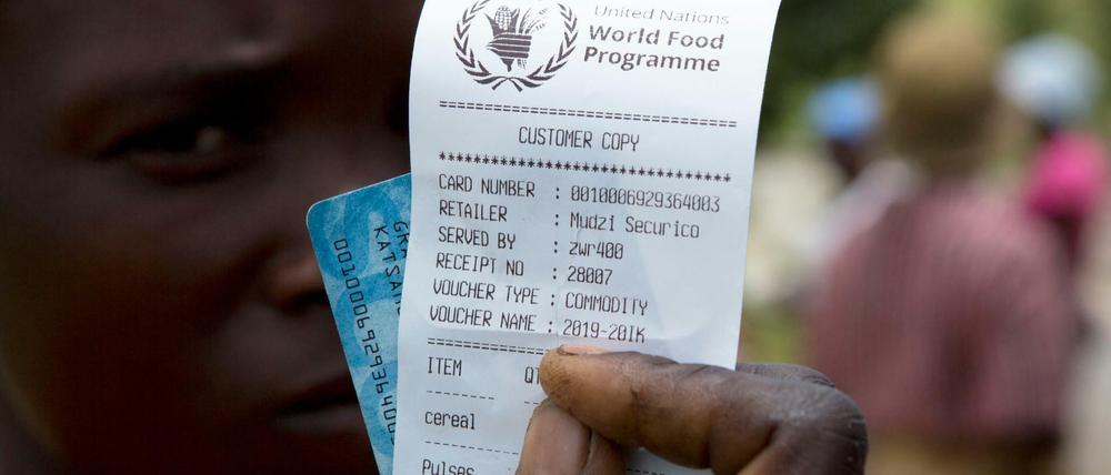 Eine Frau in Zimbabwe hält einen Gutschein für Nahrungsmittelhilfe in die Kamera.