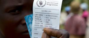 Eine Frau in Zimbabwe hält einen Gutschein für Nahrungsmittelhilfe in die Kamera. 