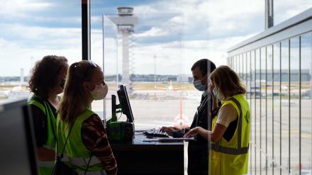 Zwei Komparsinnen in grünen Warnwesten warten beim Probelauf im BER-Terminal 1 auf das Boarding.