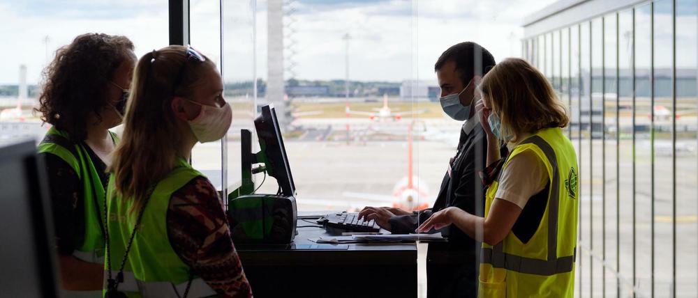 Zwei Komparsinnen in grünen Warnwesten warten beim Probelauf im BER-Terminal 1 auf das Boarding.