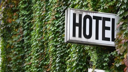 Ein Schild "Hotel" ist an der mit Efeu bewachsenden Wand eines Gebäudes angebracht.