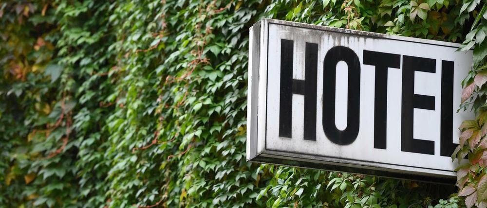 Ein Schild "Hotel" ist an der mit Efeu bewachsenden Wand eines Gebäudes angebracht.