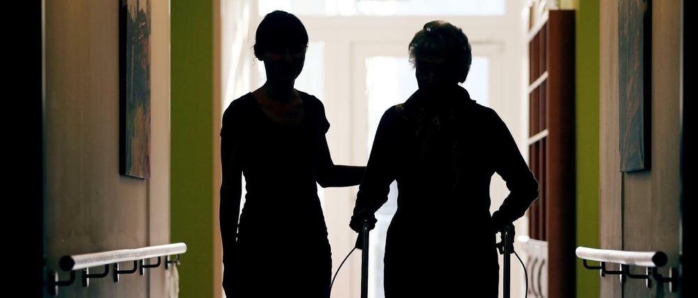 Düsseldorf: Eine Pflegekraft (l) begleitet die Bewohnerin eines Altenheims beim Gang über den Flur.