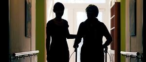 Düsseldorf: Eine Pflegekraft (l) begleitet die Bewohnerin eines Altenheims beim Gang über den Flur.