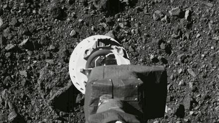 Ein Roboterarm saugt eine Probe von einer geröllbedeckten Oberfläche auf.