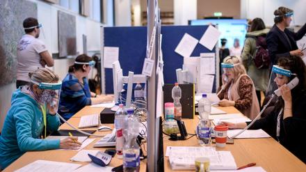 Mitarbeiter des Gesundheitsamtes Mitte mit Gesichtsschutzschirm telefonieren im Lagezentrum.