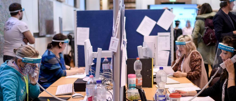 Mitarbeiter des Gesundheitsamtes Mitte mit Gesichtsschutzschirm telefonieren im Lagezentrum.