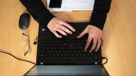 Im Bild ist ein Laptop, auf der eine Person mit beiden Händen tippt.