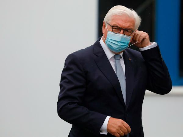Frank-Walter Steinmeier setzt sich einen blauen Mund-Nasen-Schutz auf.