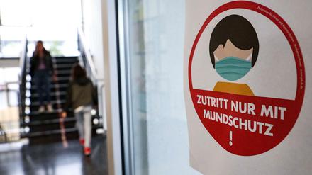 In einer hessischen Schule weist ein Schild auf die Maskenpflicht hin. 
