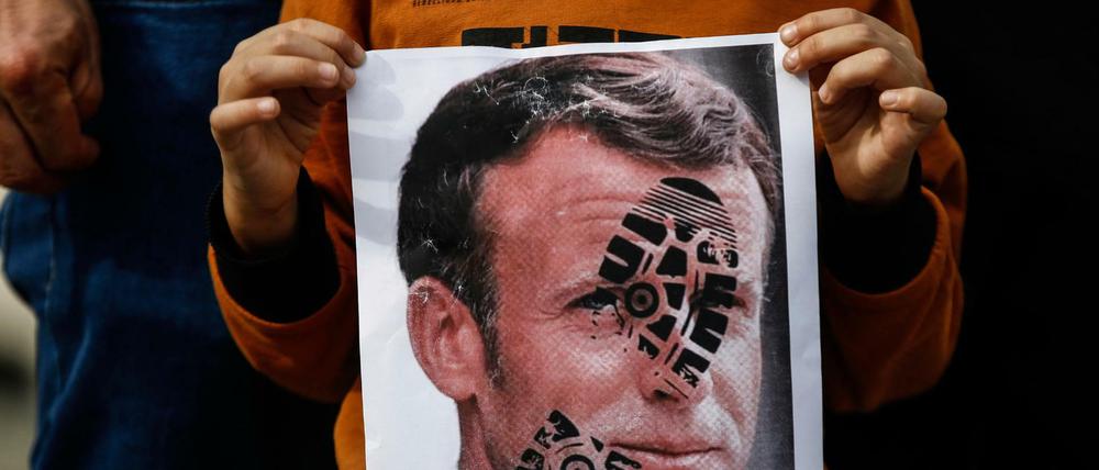 Ein Kind hält ein mit einem Schuhabdruck versehenes Foto des französischen Staatschefs Emmanuel Macron in Istanbul in die Kamera.