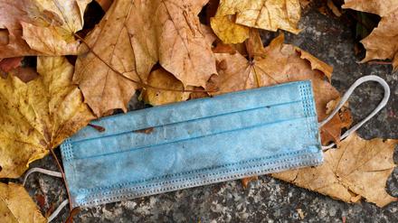 Ein Einweg-Mund-Nasenschutz im Herbstlaub: Zahlreiche Verbände der Berliner Wirtschaft rufen die Bevölkerung auf, Schutzmaßnahmen umzusetzen, um weitere Schließungen durch die Politik zu verhindern.