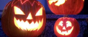 Geschnitzte Halloween-Kürbisse mit Kerzen stehen vor einem Haus. Politiker und Mediziner warnen davor, von Tür zu Tür zu gehen und nach Süßigkeiten zu fragen.