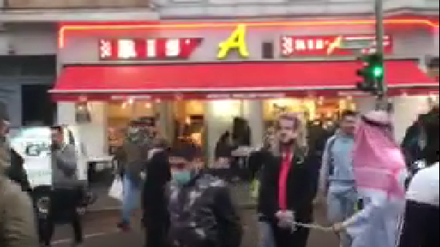 Ein Mann mit Macron-Maske wird die Sonnenallee heruntergeführt.