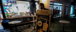 Der Berliner Café-Betreiber John Bleys räumt am Sonntagabend einen Aufsteller ab, um seinen Laden für einen Monat zu schließen. Das sehen die jüngsten Auflagen zur Bekämpfung der Pandemie vor, die das Abgeordnetenhaus am Sonntag in einer Sondersitzung verabschiedet hat.