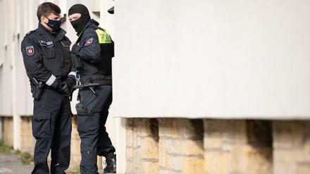 Polizisten stehen im Rahmen einer Durchsuchung vor einem Wohnhaus. 
