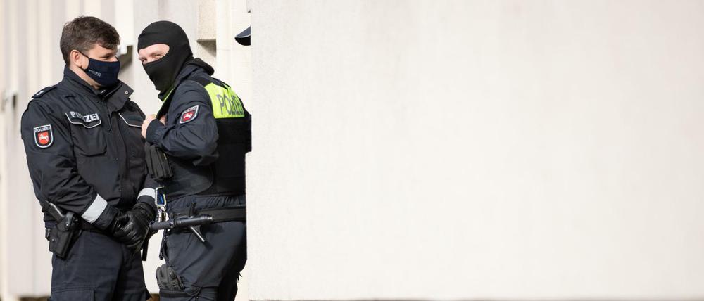 Polizisten stehen im Rahmen einer Durchsuchung vor einem Wohnhaus.