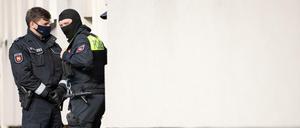 Polizisten stehen im Rahmen einer Durchsuchung vor einem Wohnhaus. 