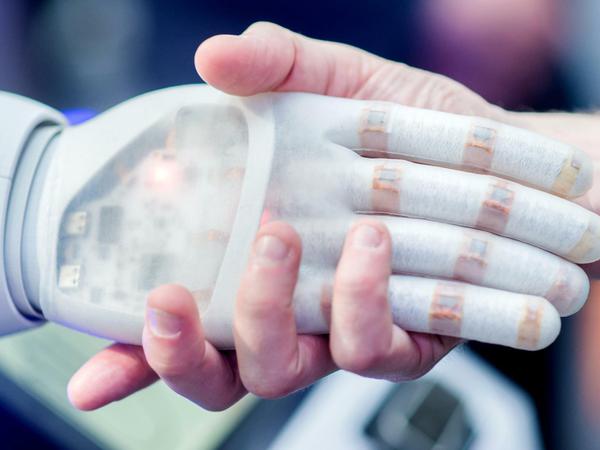Handschlag zwischen einer Roboterhand und einem Menschen.