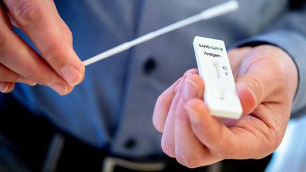 Ein Mann hält einen Schnelltest zur Erkennung des Coronavirus und ein Teststäbchen in den Händen.