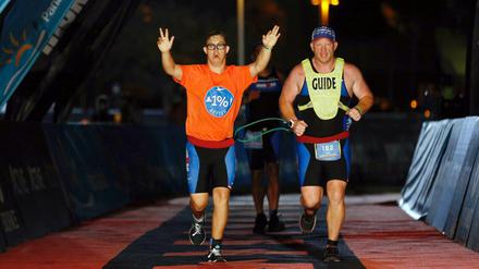 Traum erfüllt: Mit hochgestreckten Armen läuft Chris Nikoc (l) neben seinem Trainer Dan Grieb beim Ironman 2020 über die Zielline. 