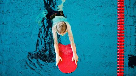 Kind mit Schwimmbrett im Wasser.