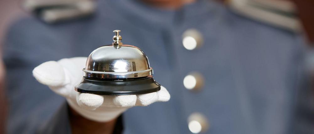 Hotelglocke auf der Hand von einem Concierge im Hotel (Symbolbild).