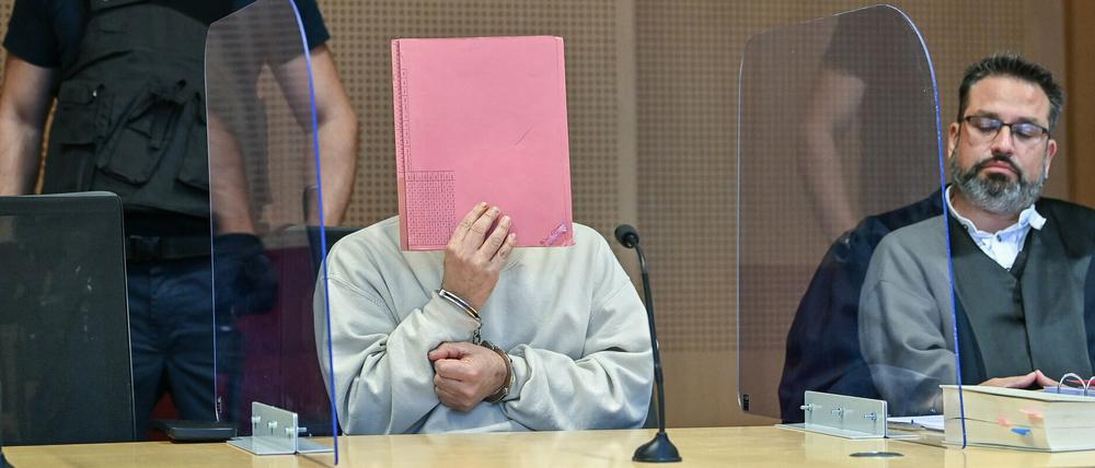  Ein wegen des Überfalls auf die Diskothek «Frosch» im Jahr 2018 angeklagter Mann (M) sitzt in Handschellen und vor Blicken geschützt mit einer Akte vor seinem Gesicht zum Prozessauftakt in einem Verhandlungssaal.